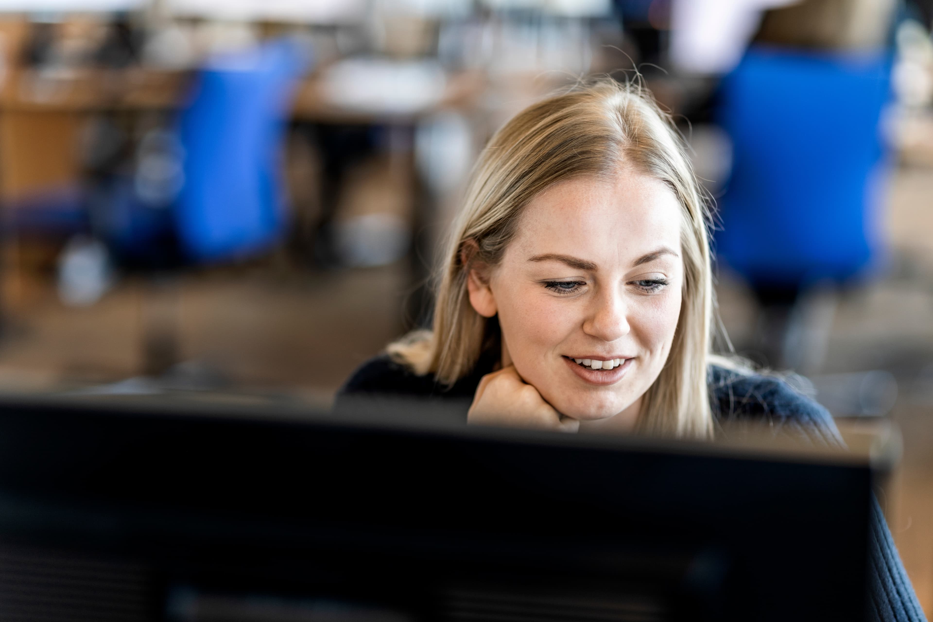 A DFDS employee sits at their desk and looks at a computer monitor in an office