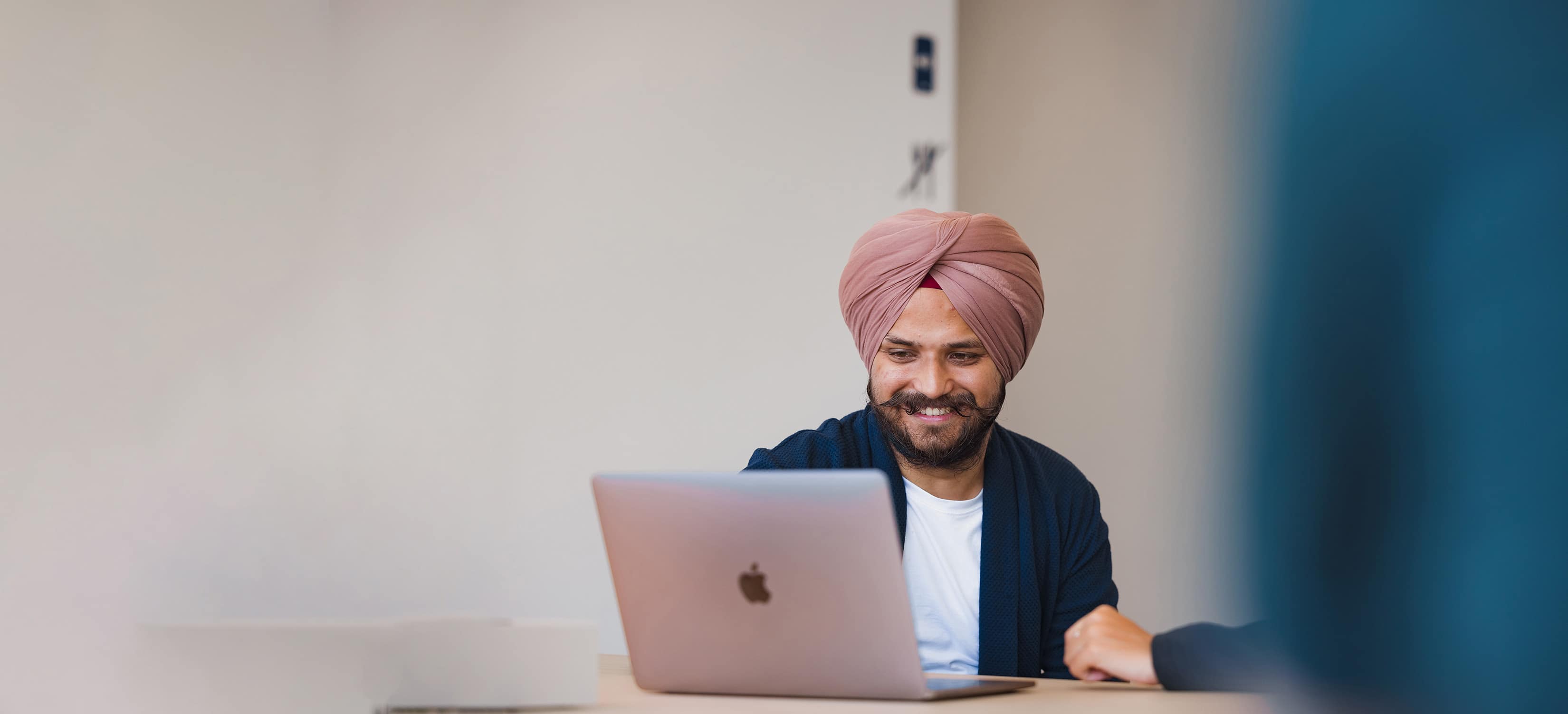 A DFDS employee, sitting at a desk, smiles while looking at a laptop