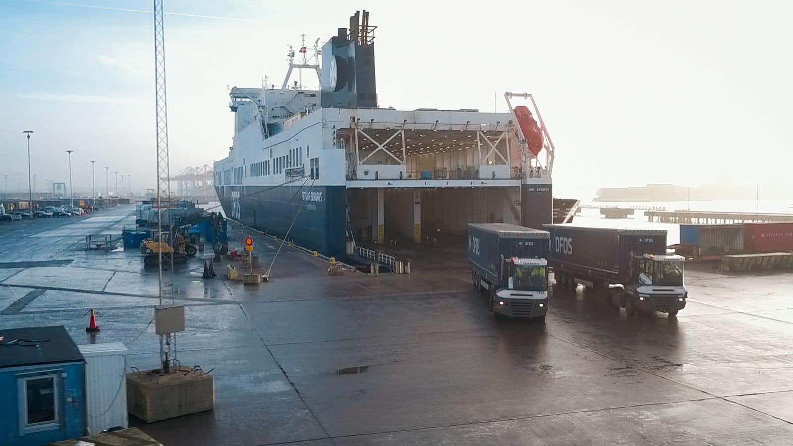 Two DFDS trucks unloading from a ship at the dock
