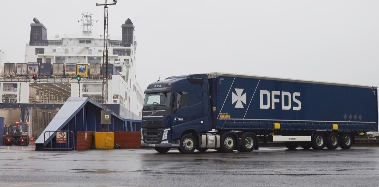 A DFDS truck arrives a ferry terminal and prepares to roll onto a DFDS vessel on a cloudy day