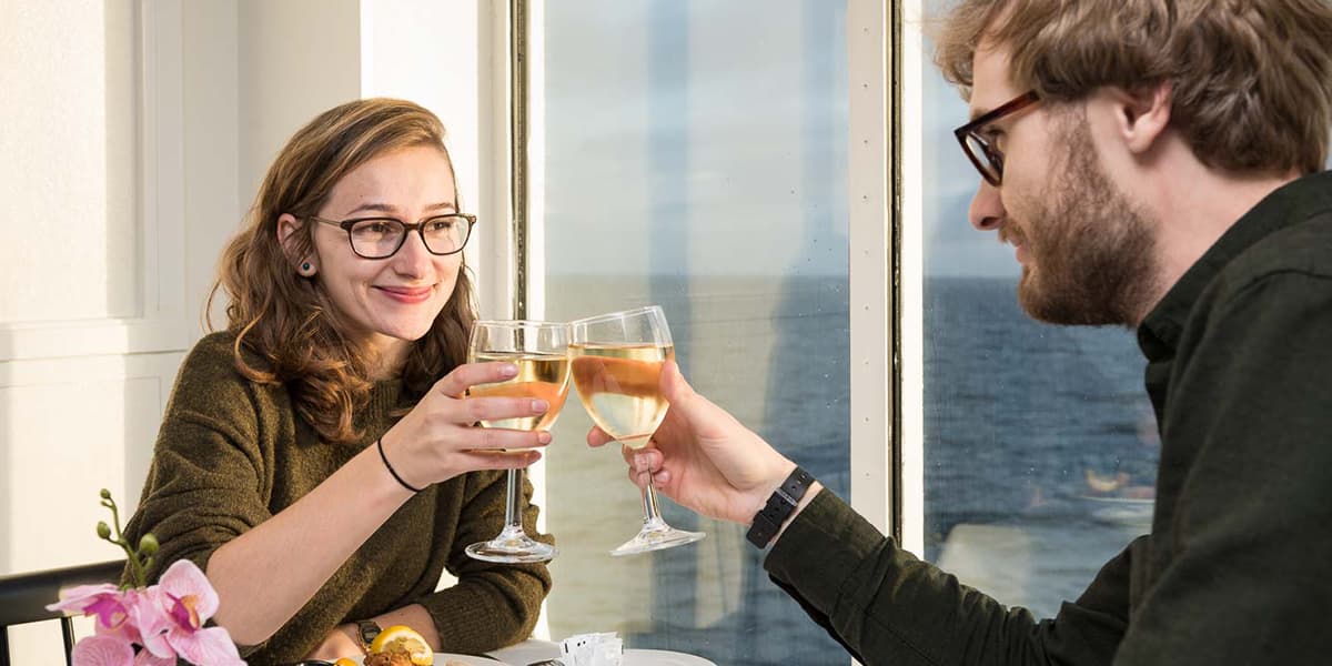 Couple making a toast in Explorer's Kitchen onboard restaurant